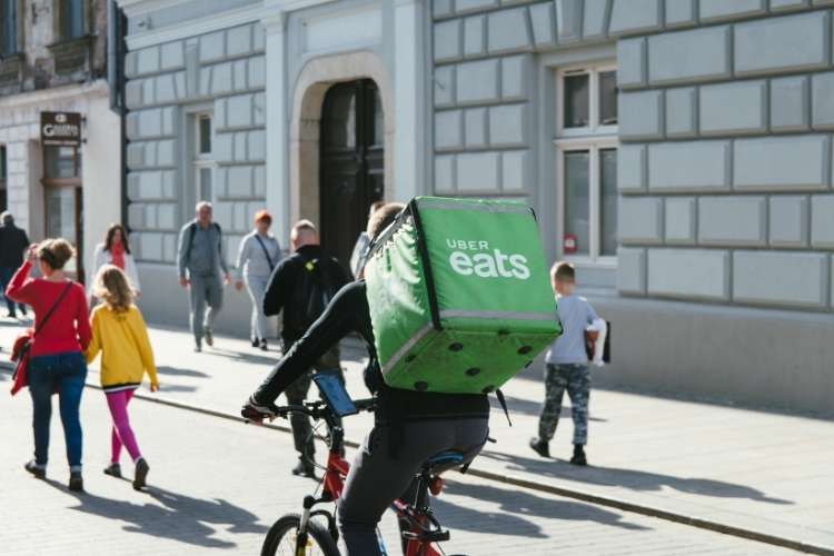 Entregador da Uber Eats pedalando bicicleta pelas ruas.