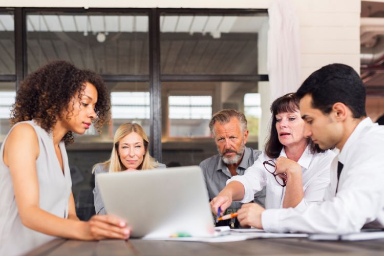 Equipe olhando para notebook com expressões sérias, conversando.