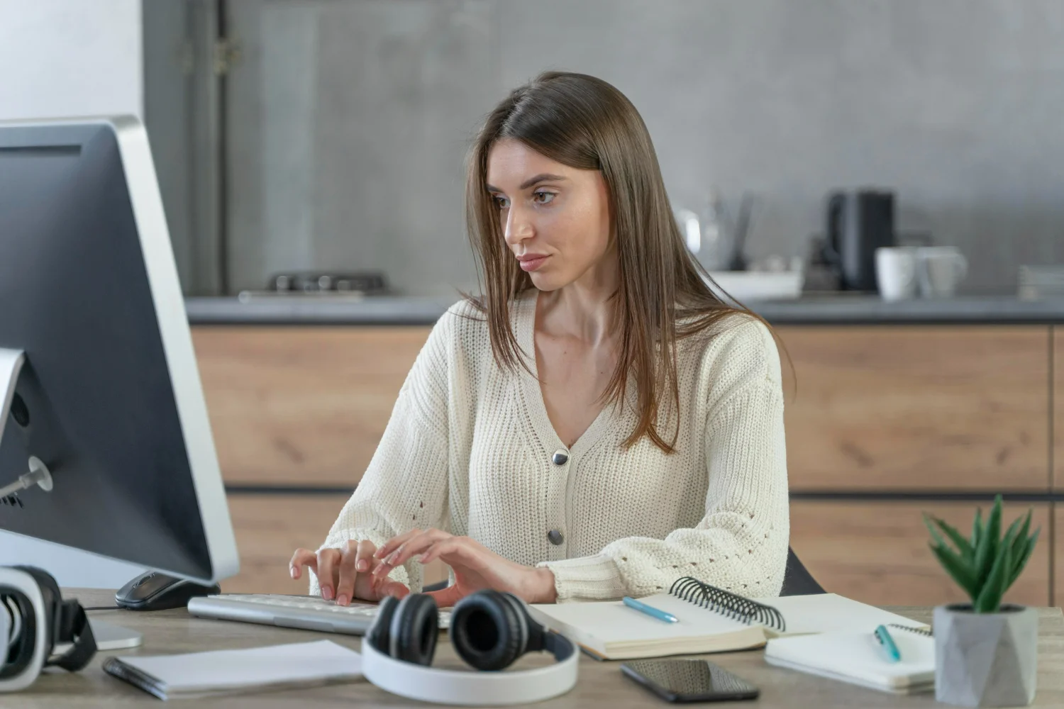 Mulher branca sentada utilizando um computador para estudar e trabalhar com gestão financeira nos marketplaces